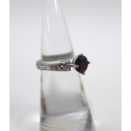 26 - Garnet and diamond ring on an 18ct white gold engraved band, with a circular claw set garnet and eig... 