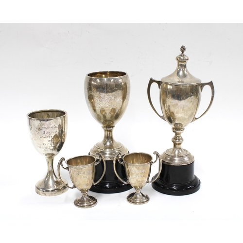 83 - Five silver sporting trophy cups, two with an ebonised stand, all early 20th century with various ha... 