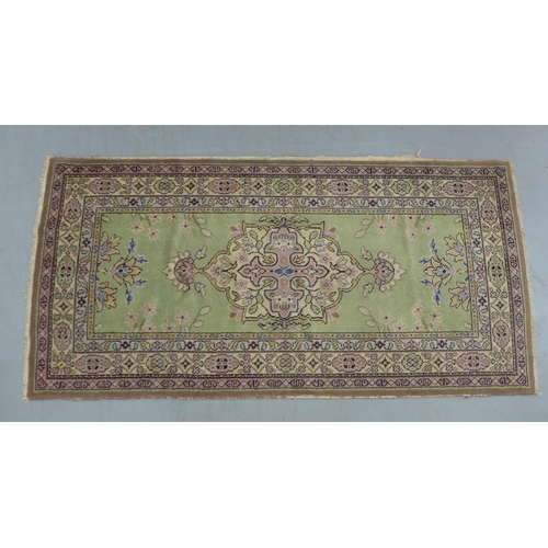 530 - Eastern wool rug with sage green field and foliate medallion,  201 x 97cm.