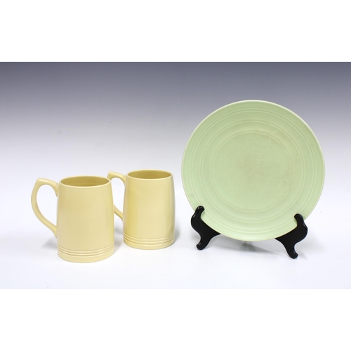 102 - KEITH MURRAY for Wedgwood, a pair of straw matt glazed tankards and a pale green bowl on conical foo... 