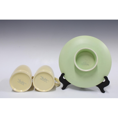 102 - KEITH MURRAY for Wedgwood, a pair of straw matt glazed tankards and a pale green bowl on conical foo... 