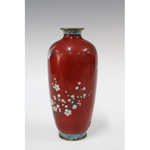 150 - Cloisonne vase with a pattern of birds perched on blossom branches against a red ground, 22cm high.