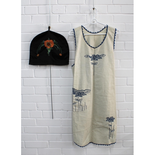 490 - Crewel work pinafore, together with a black embroidered tea cosy (2)