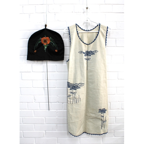 490 - Crewel work pinafore, together with a black embroidered tea cosy (2)