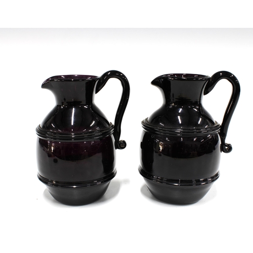 121 - Two early 19th century dark amethyst glass cream jugs, with strapwork handles, 15cm (2)