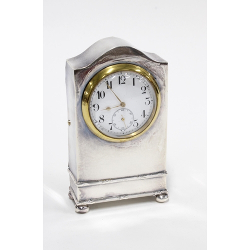 23 - An Edwardian silver dressing table clock, Chester 1910, simple case with an arched top, standing on ... 