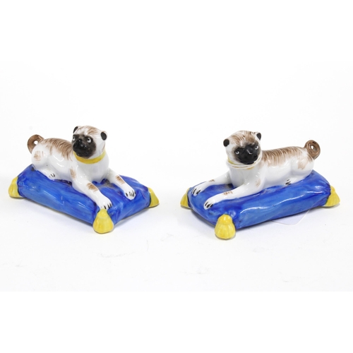 428 - a pair of continental porcelain pug dogs on blue cushions, 7cm long (2)