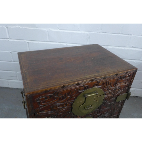 503 - A chinoiserie dragon carved box with brass mounts, the doors opening to reveal an assortment of draw... 