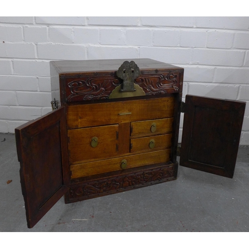 503 - A chinoiserie dragon carved box with brass mounts, the doors opening to reveal an assortment of draw... 