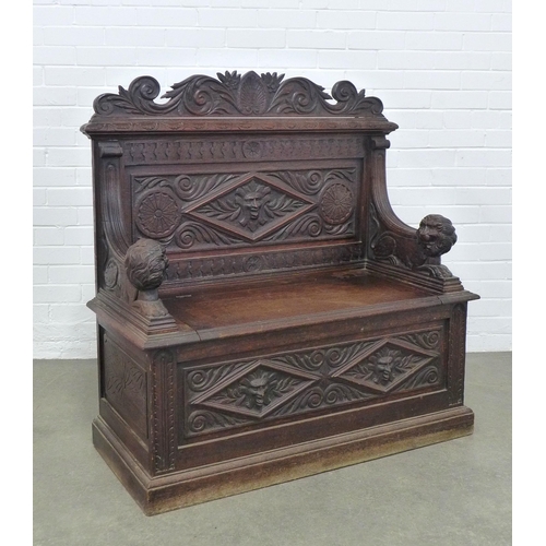 A carved oak bench, with shaped top rail and lion handles, the seat with a lift up compartment, 106 x 96 x 48cm.