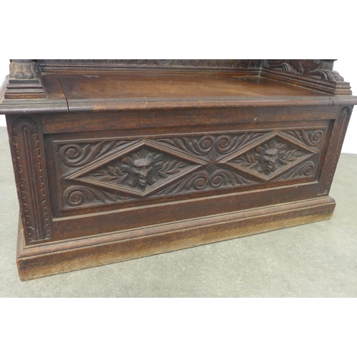 224 - A carved oak bench, with shaped top rail and lion handles, the seat with a lift up compartment, 106 ... 