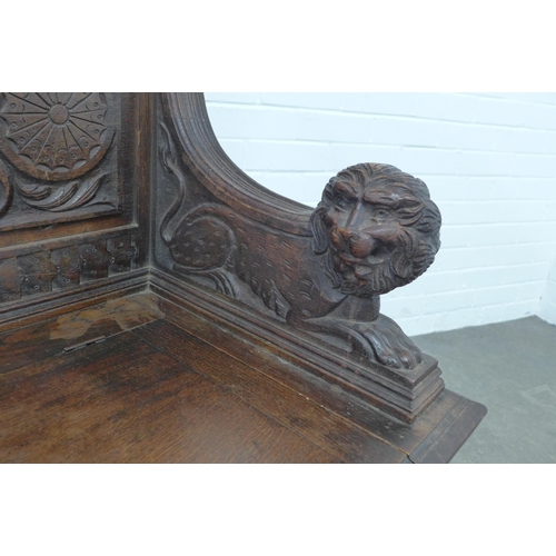 224 - A carved oak bench, with shaped top rail and lion handles, the seat with a lift up compartment, 106 ... 