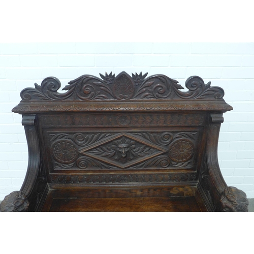 224 - A carved oak bench, with shaped top rail and lion handles, the seat with a lift up compartment, 106 ... 