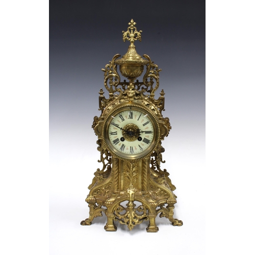 381 - French brass mantle clock, rococo style with an urn surmount over an enamel dial with roman numerals... 