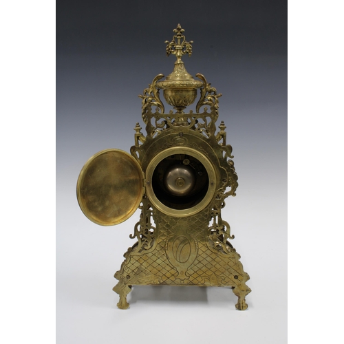 381 - French brass mantle clock, rococo style with an urn surmount over an enamel dial with roman numerals... 