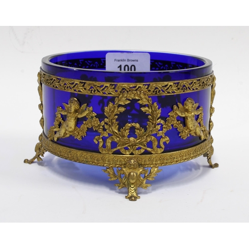 100 - 19th century blue glass bowl in a circular gilt metal stand with cherubs and garlands, on four outsw... 