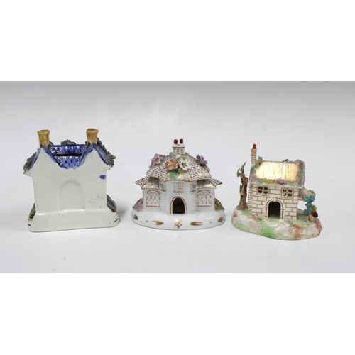 104 - Two Staffordshire pastille burner cottages and a Staffordshire pottery money bank in the form of a h... 