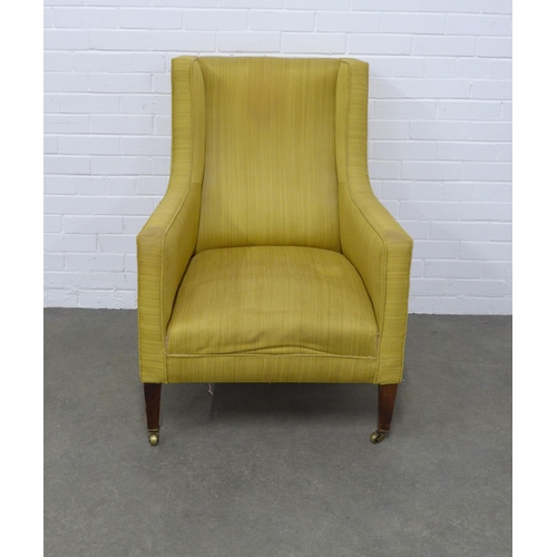 240 - Edwardian upholstered wing armchair on mahogany legs with brass caps and castors, 73 x 98 x 59cm.