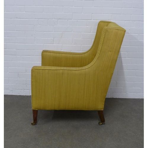 240 - Edwardian upholstered wing armchair on mahogany legs with brass caps and castors, 73 x 98 x 59cm.