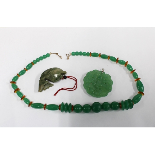 62 - Two carved jadeite pendants, one in the form of a fish, and a strand of coloured beads (3)