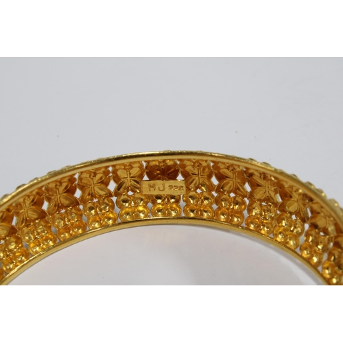 119 - A yellow metal bangle, possibly Indian, of stiff hinged form with pierced design, (tests as 22ct) to... 