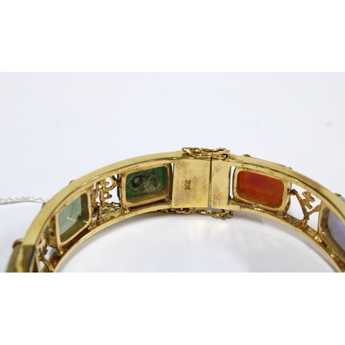 16 - Yellow metal bangle with coloured hardstone panels  interspersed with calligraphy, possibly Chinese,... 