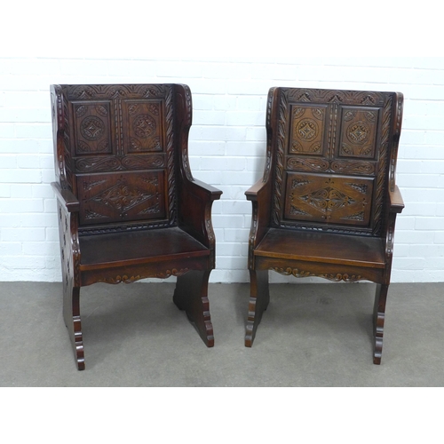 284 - Pair of Baronial style oak armchairs, with carved backs and solid seat, stylised rosettes to the win... 