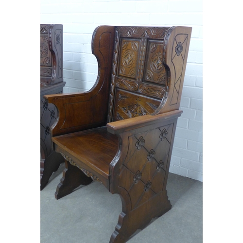 284 - Pair of Baronial style oak armchairs, with carved backs and solid seat, stylised rosettes to the win... 