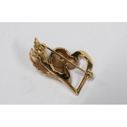 99 - Unmarked yellow metal dogs head and wings heart shaped brooch, the dogs head with an emerald for its... 