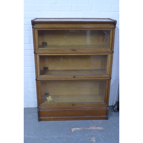 286 - Inglesants oak three tier sectional bookcase, with glass fronts and brass label. (two glass panes a/... 