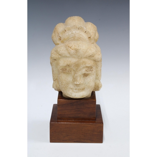 360 - Stone head of a boddhisatva, on a stepped wooden stand, 28cm