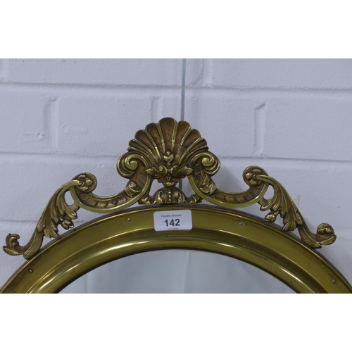 142 - A circular brass framed wall mirror with shell surmount, 46cm diameter