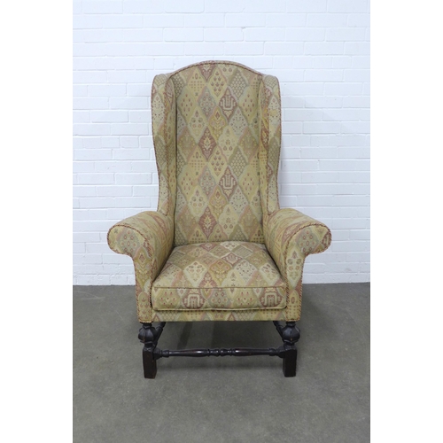 206 - High back wing armchair, upholstered and with dark oak legs and stretchers, 93 x 141 x 53cm.