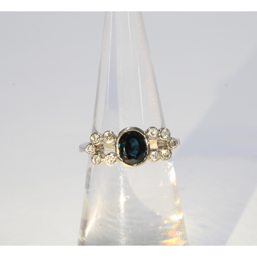 64 - Sapphire and diamond ring set in unmarked white metal, the central sapphire in a rub over collet set... 