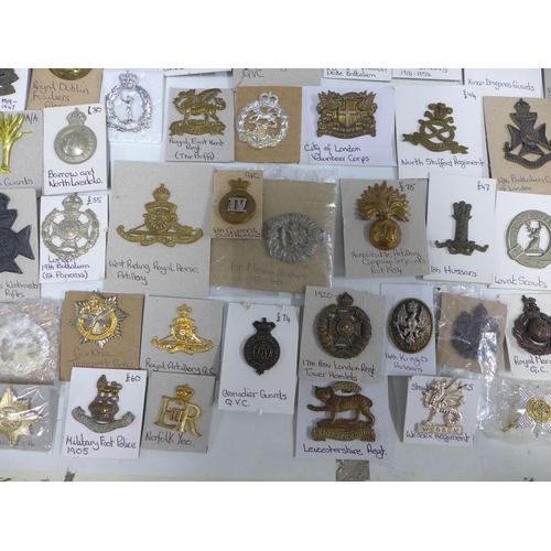 A large collection of military cap badges