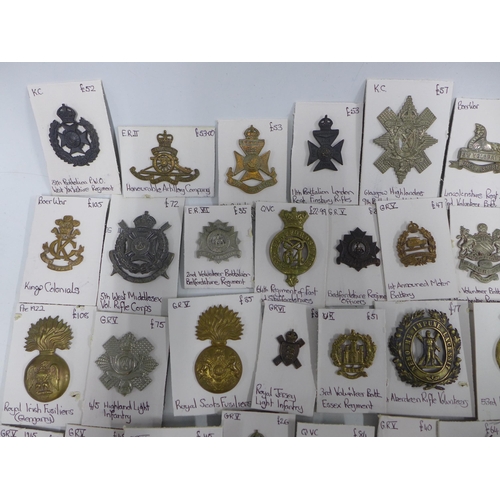 A large collection of military cap badges