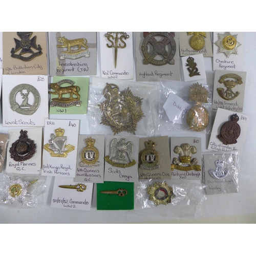 A large collection of military cap badges