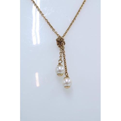 6 - French gold necklace with knotted ends suspending two pearls, indistinct poincon mark to clasp
