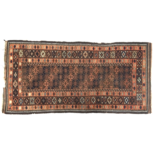 662 - A Persian rug in tones of pink, indigo, and brown, the centre field with narrow tile like pattern, s... 