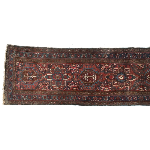 668 - A long runner rug in tones of red, brown, and indigo, with accents of white, surrounded by a triple ... 