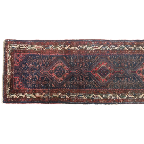 669 - A long madder and indigo runner rug, the central lozenges surrounded by a triple border, 105x480cm