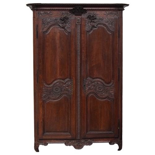 643 - A late 18th century provincial chestnut armoire, fitted with two fielded panel doors, carved with fl... 