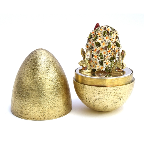 84 - A silver and silver gilt egg of typical form, by Stuart Devlin, opening to reveal enamelled flowers ... 