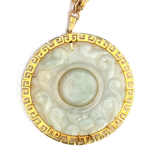 61 - Large jade pendant with central rotating disc with 9ct gold Greek key surround on a yellow metal cha... 