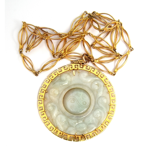 61 - Large jade pendant with central rotating disc with 9ct gold Greek key surround on a yellow metal cha... 