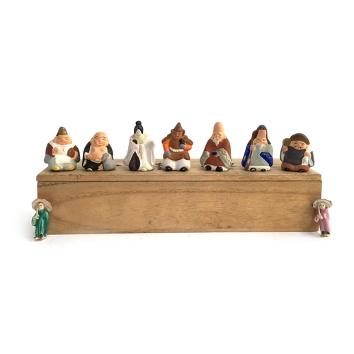 1054 - A wooden box containing 9 small Chinese ceramic figurines, each approx. 2cmH