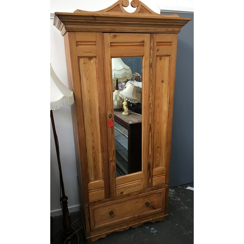 849 - A small pine hanging wardrobe with mirror door and swan neck pediment, above single drawer, 84x200cm... 