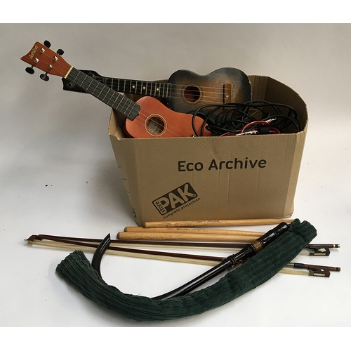150 - A mixed box of musical instrument accessories, mostly strings, two ukuleles; practice pipes; violin ... 