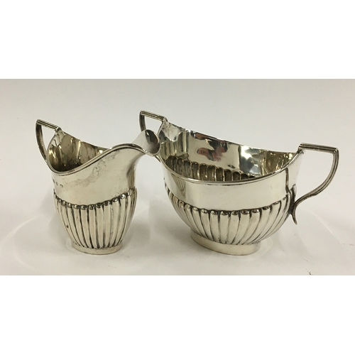 10 - A half gadrooned silver milk jug and sugar bowl by Thomas Hayes, Birmingham 1898, 5oz
