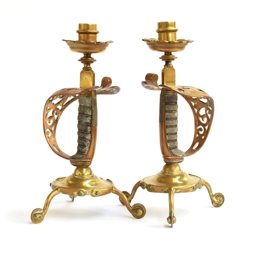 169 - A pair of brass candlesticks formed with Victorian sword hilts with shagreen and wire grips, cylindr... 